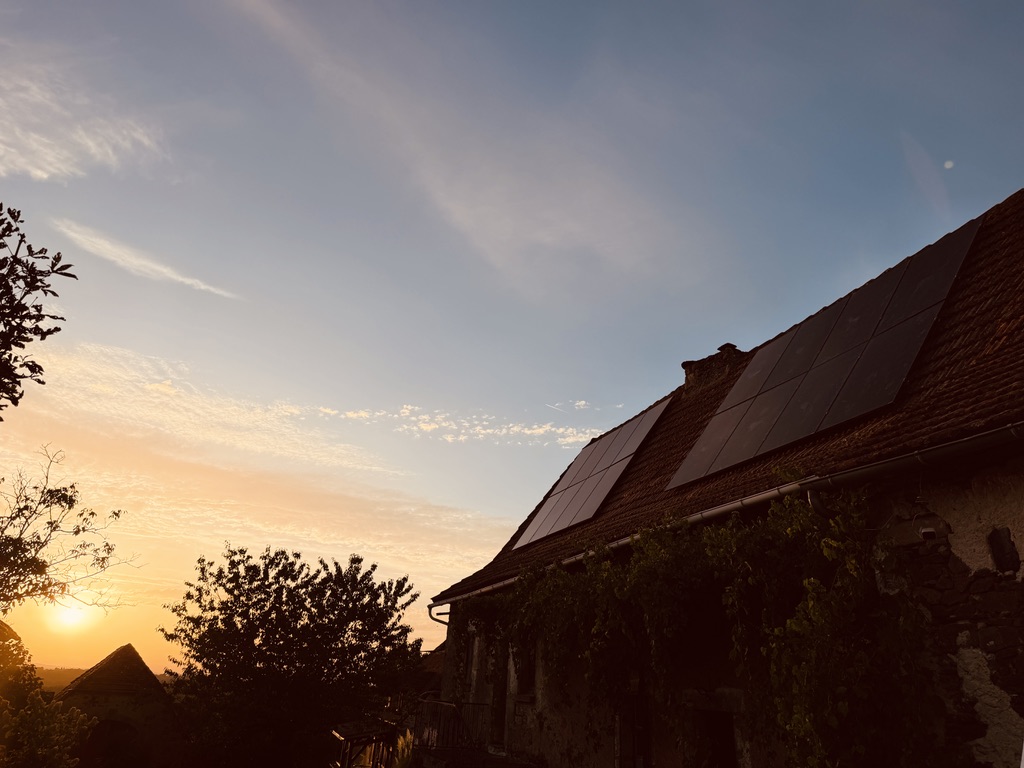 Panneaux solaires sur la toiture d’une maison en pierre au coucher du soleil